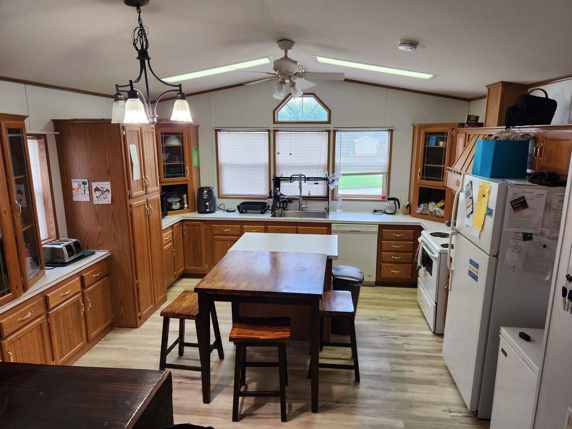 Kitchen with wooden cabinets, an island, appliances, and windows.