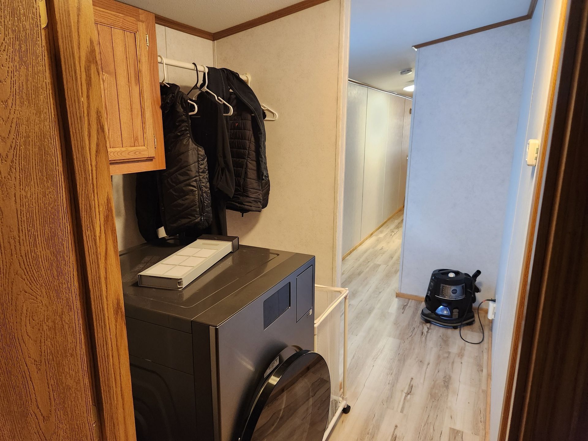 Laundry area with washer, dryer, coats, and hallway.