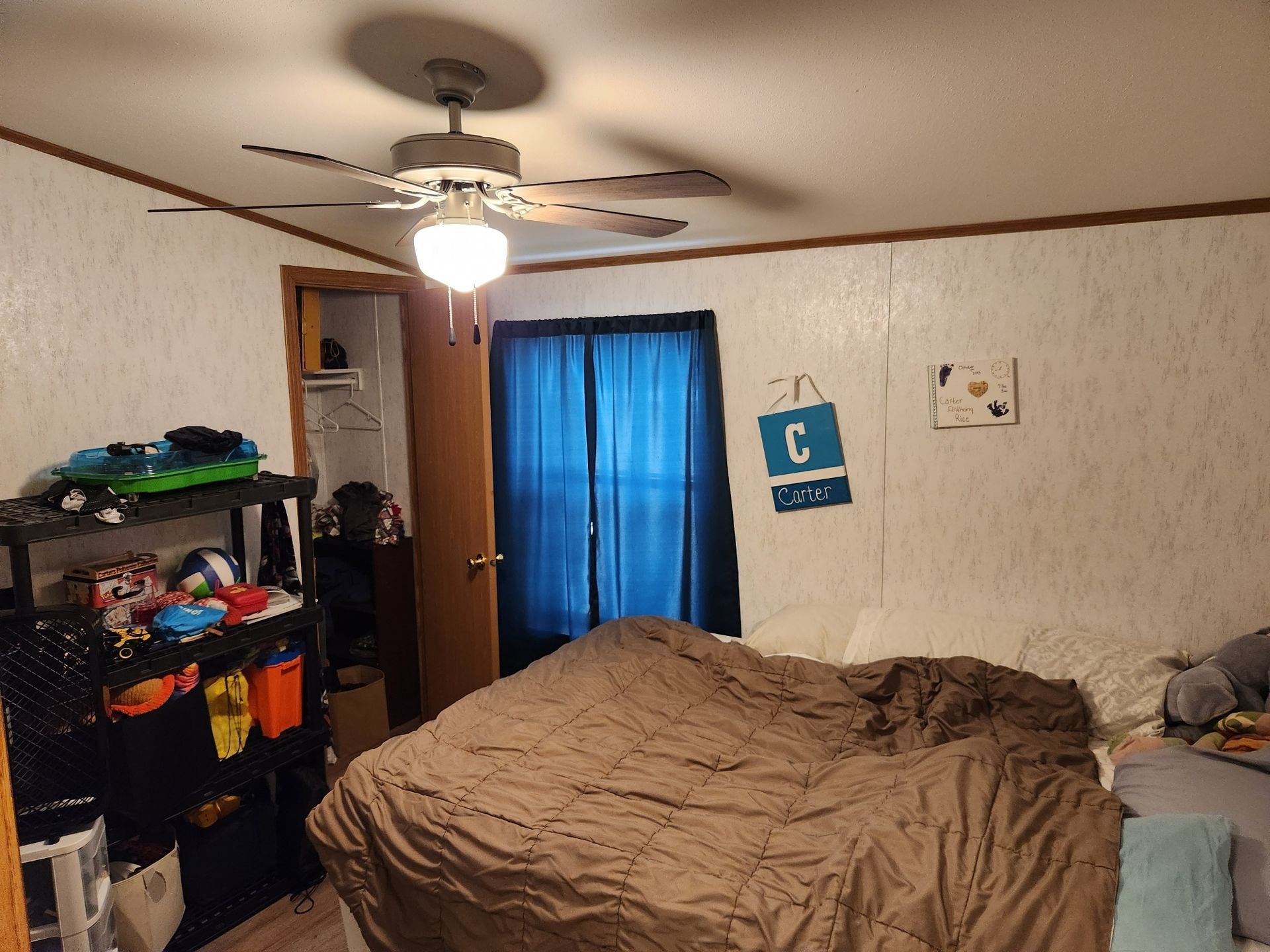 Bedroom with bed, closet, and shelf; a ceiling fan hangs overhead.