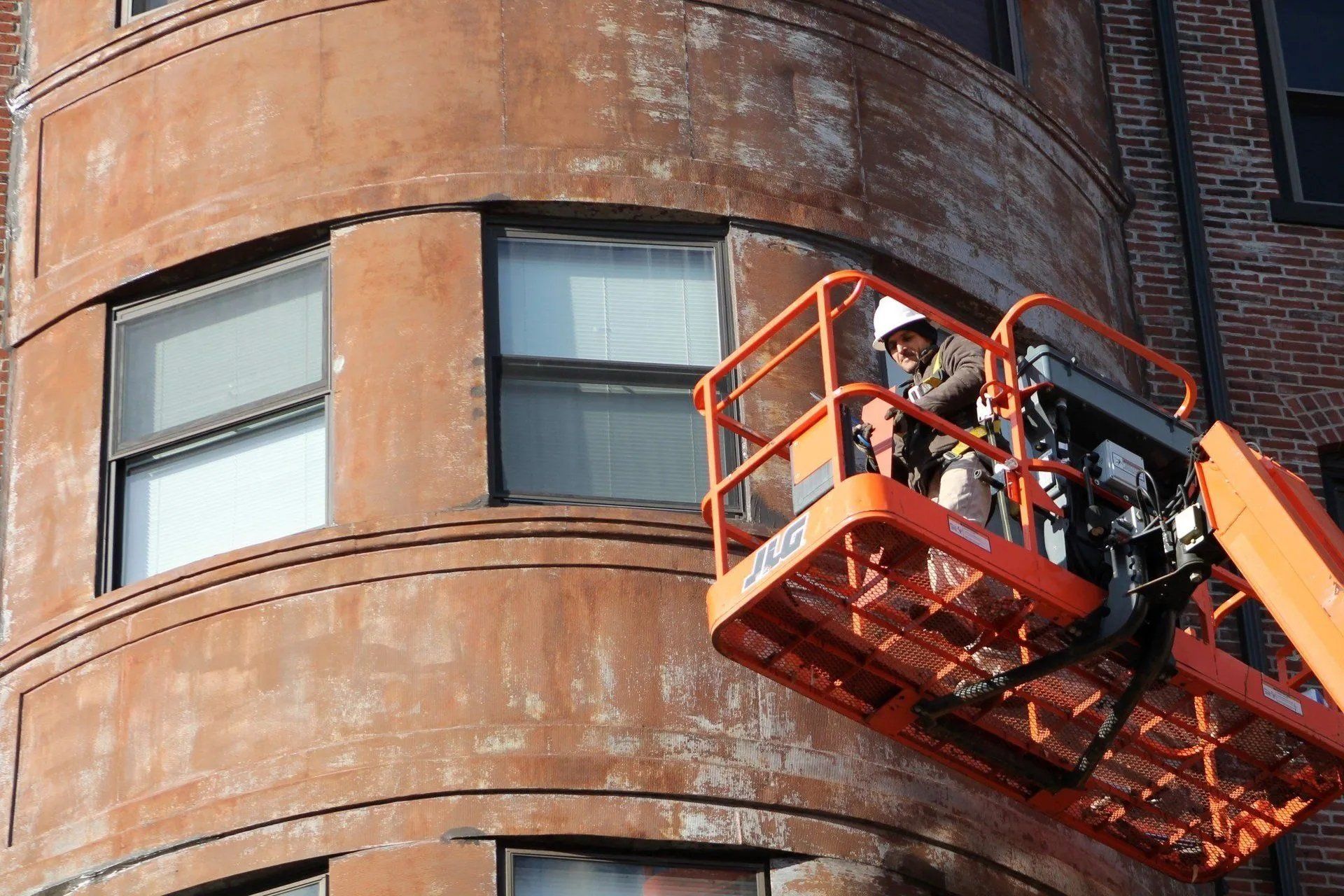 Man on a lift platform repairing the side of a building