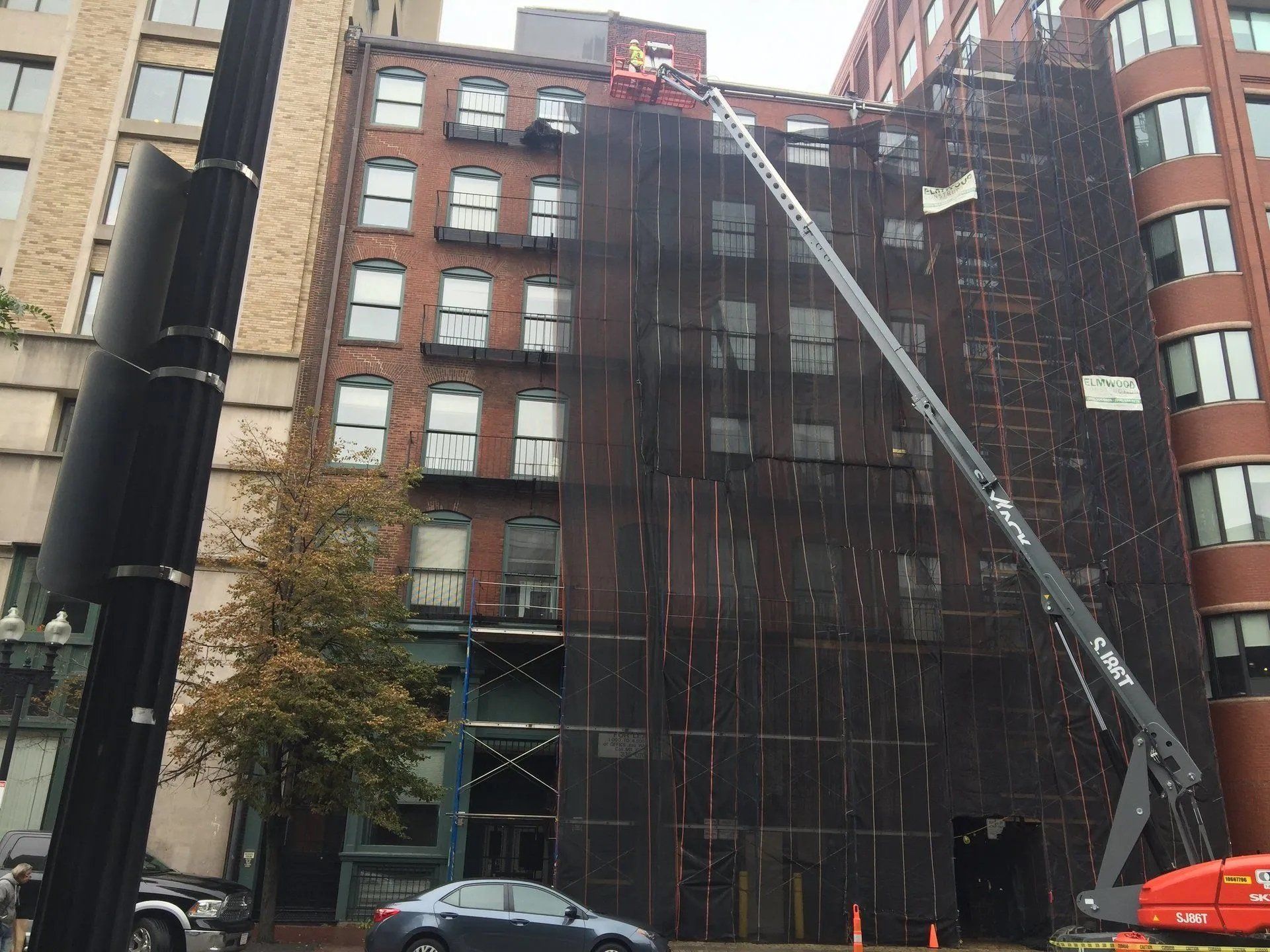 Man on an aerial lift next to a building with black safety net
