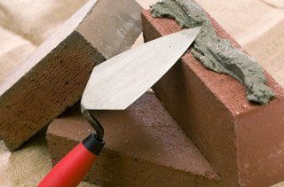 Close-up of brick spread with mortar by spade