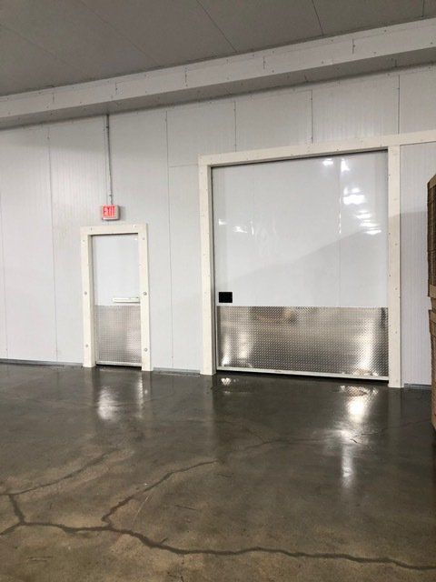 An empty room with a sliding door and a red exit sign.