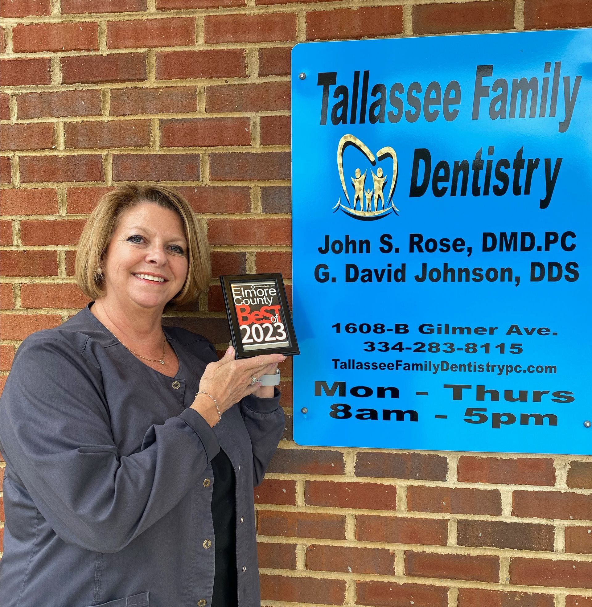 a woman is standing in front of a tallasee family dentistry sign
