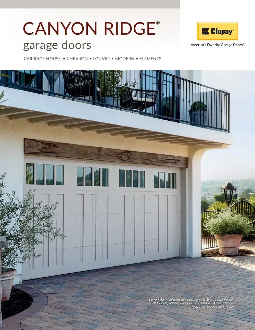 White carriage-style garage doors beneath a balcony in a modern home, with Canyon Ridge branding above
