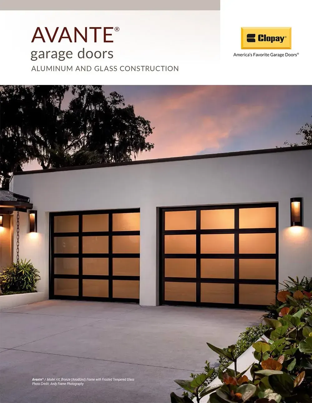Two modern black garage doors with frosted glass panels on a white home at dusk.