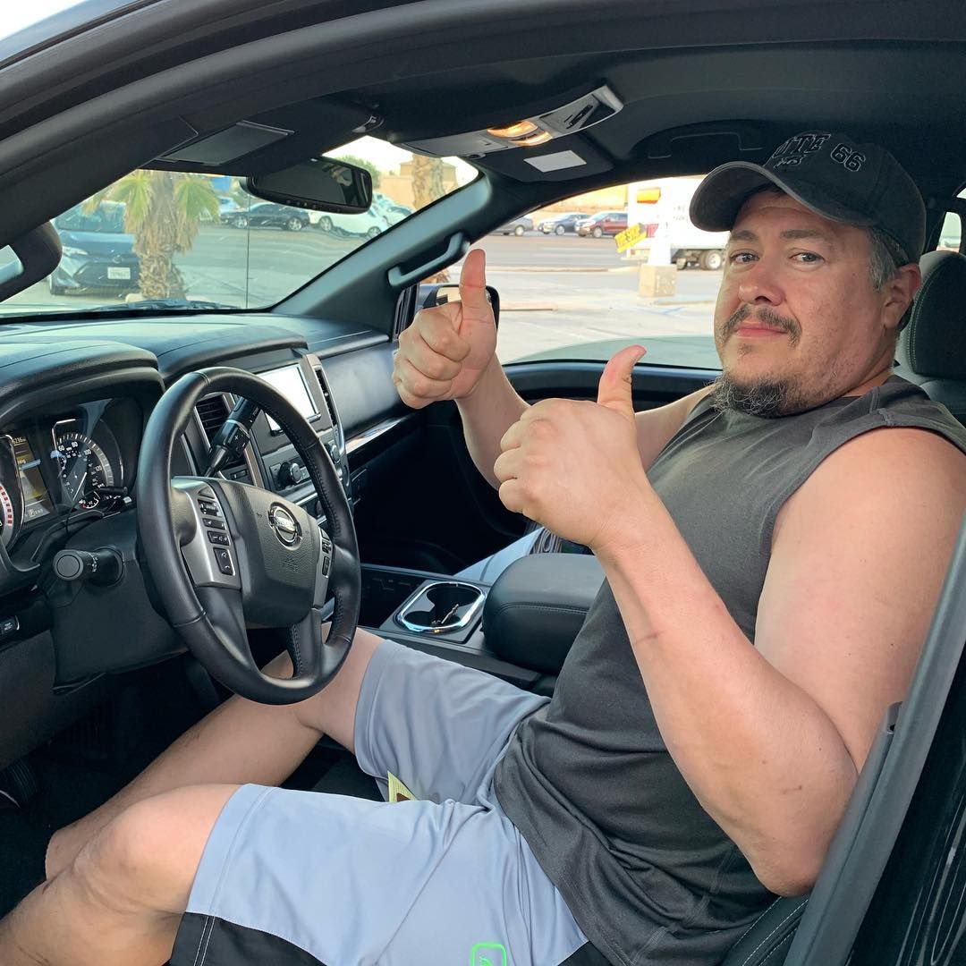 A man is giving a thumbs up while sitting in a car.