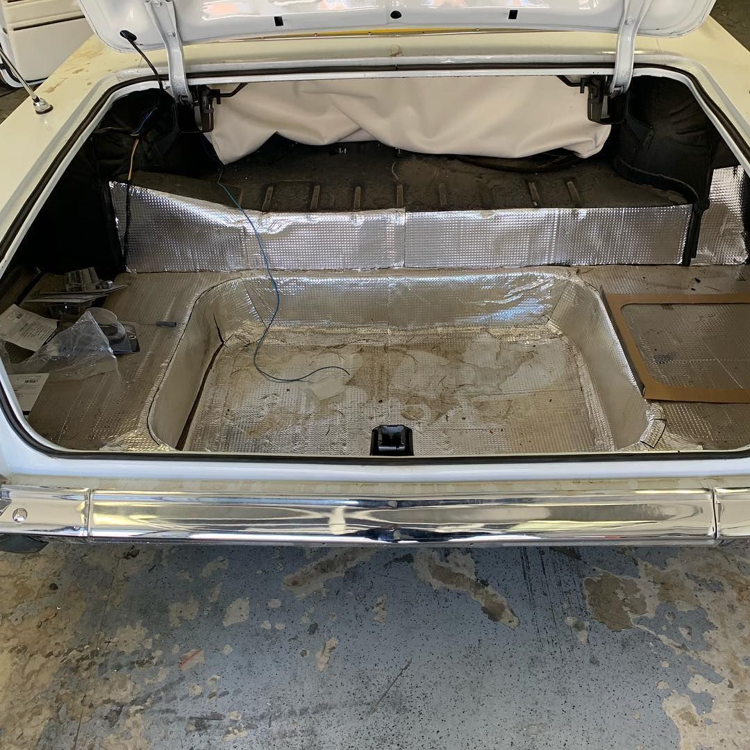 The trunk of a white car is open and empty.