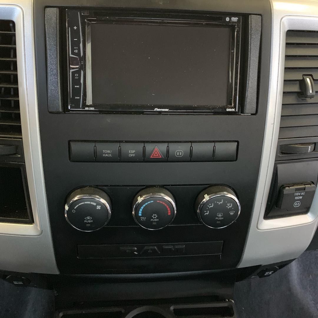 The dashboard of a dodge ram truck with a radio and climate control buttons.