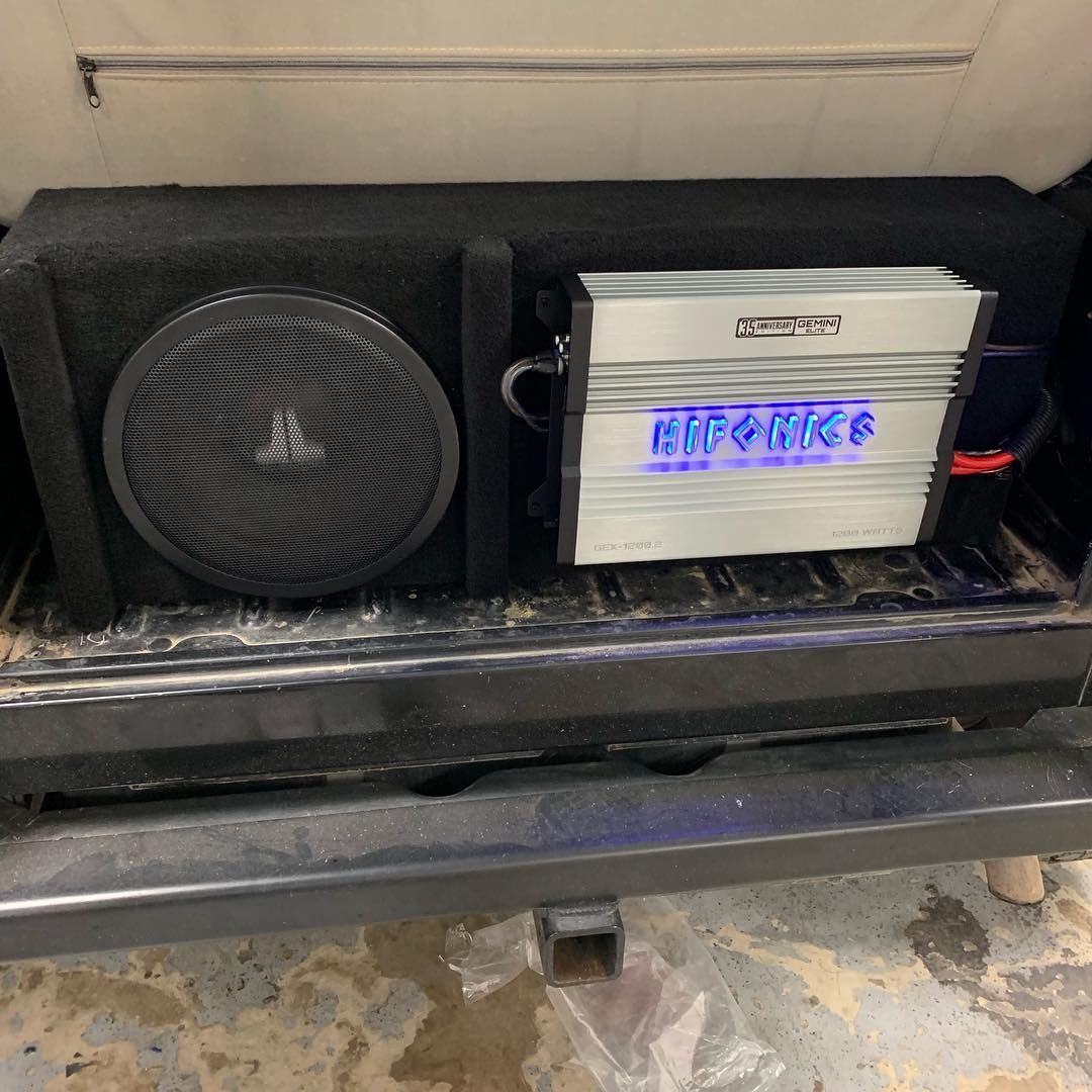 A subwoofer and amplifier are sitting on the back of a truck.