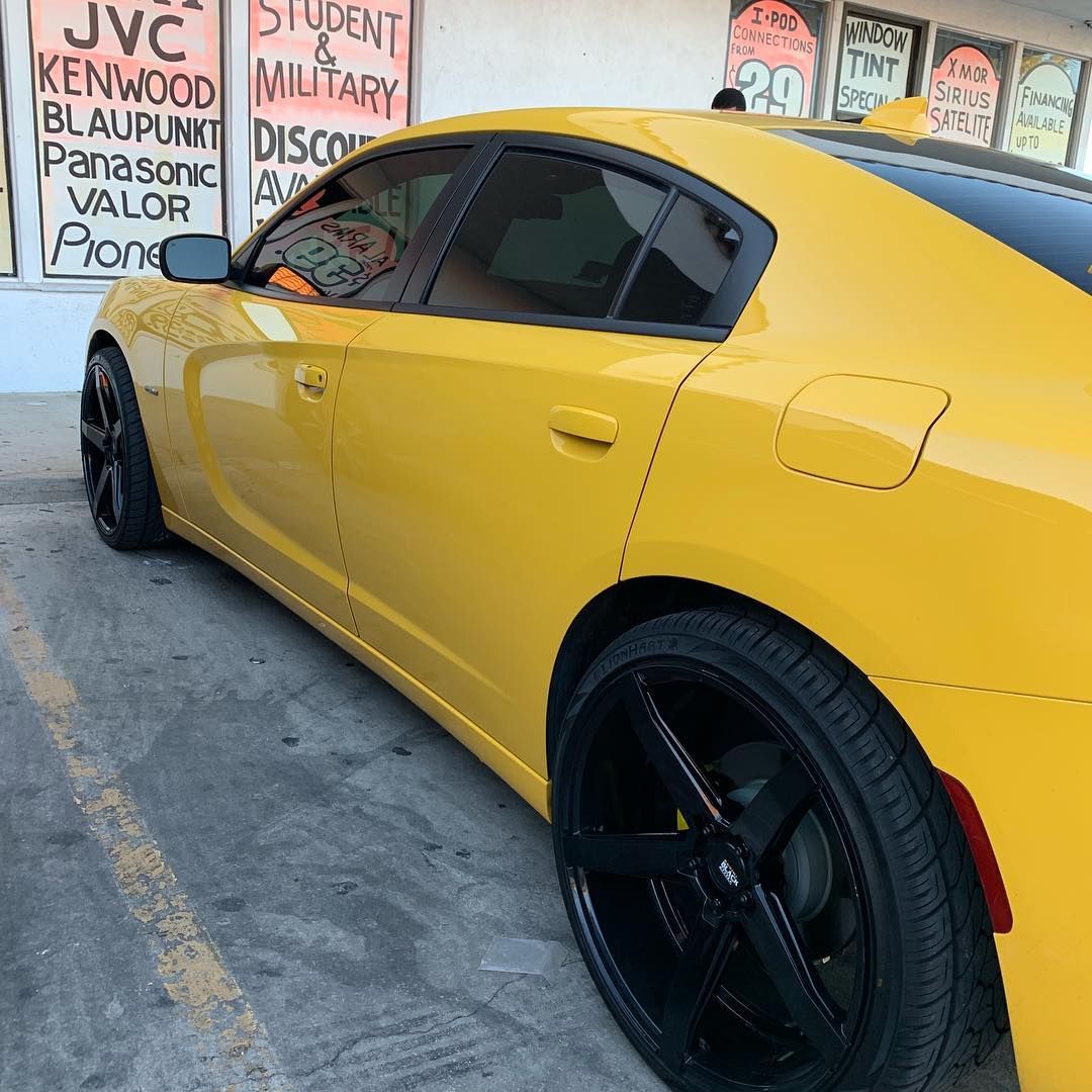 A yellow car is parked in front of a store called jvc