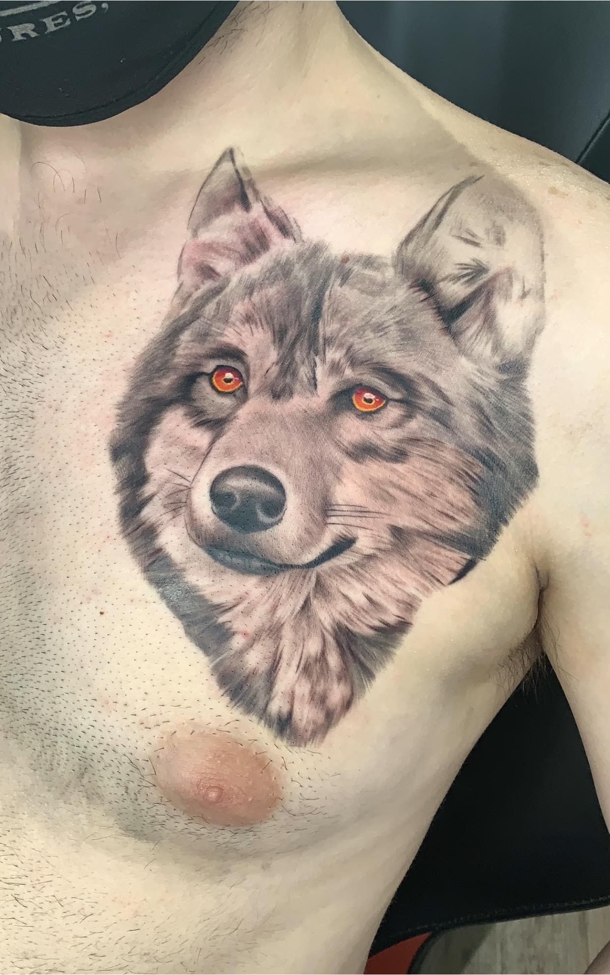 A man has a tattoo of a wolf on his chest.