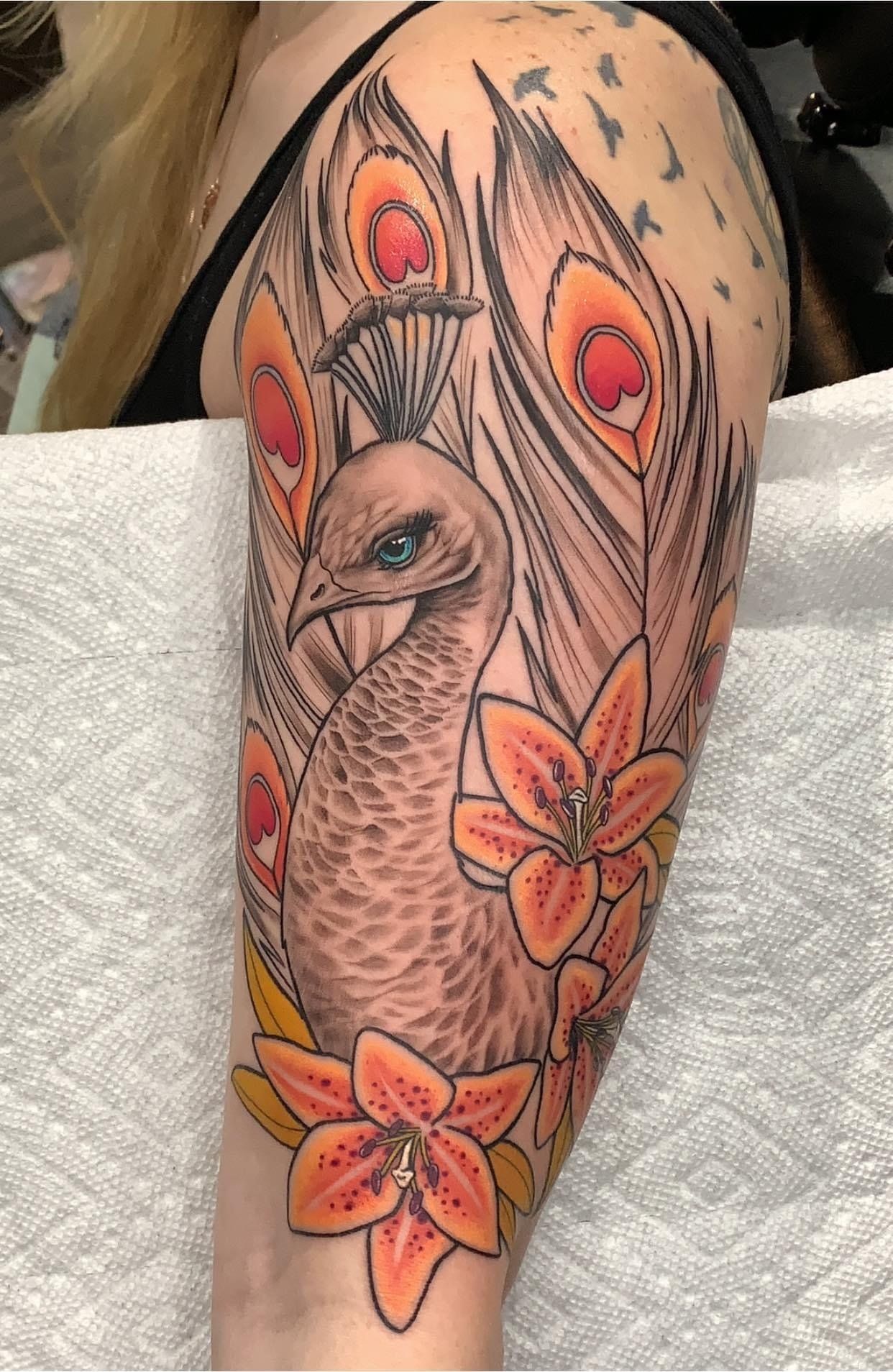 A woman has a peacock tattoo on her arm.