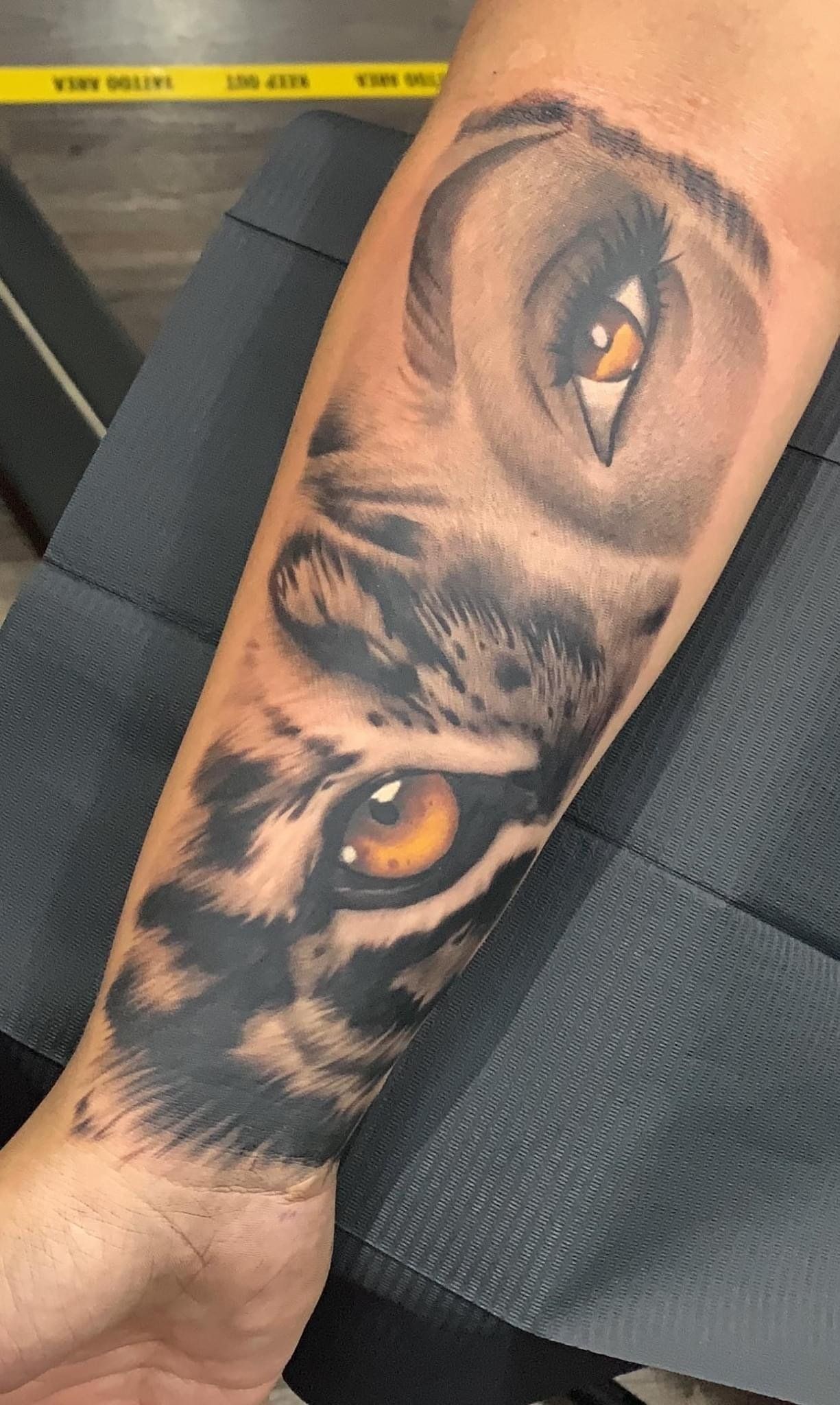 A person has a tattoo of an owl 's eye on their forearm.