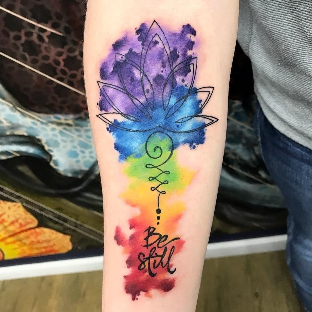 A person has a tattoo of a rainbow flower and the words be still