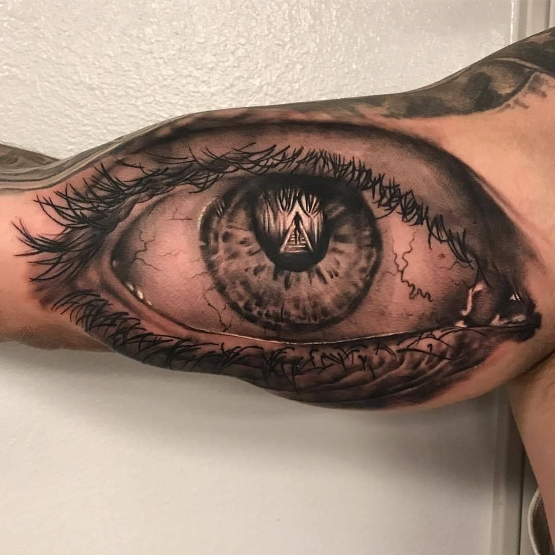 A man has a tattoo of an eye on his arm.