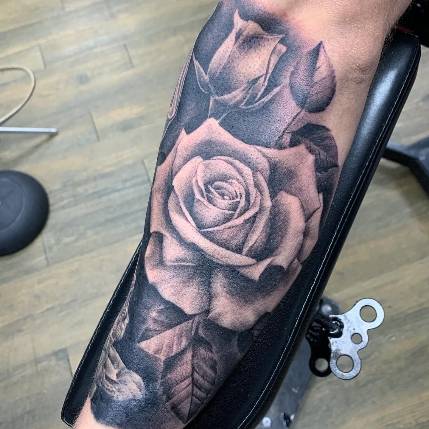 A black and white tattoo of a rose on a person 's arm