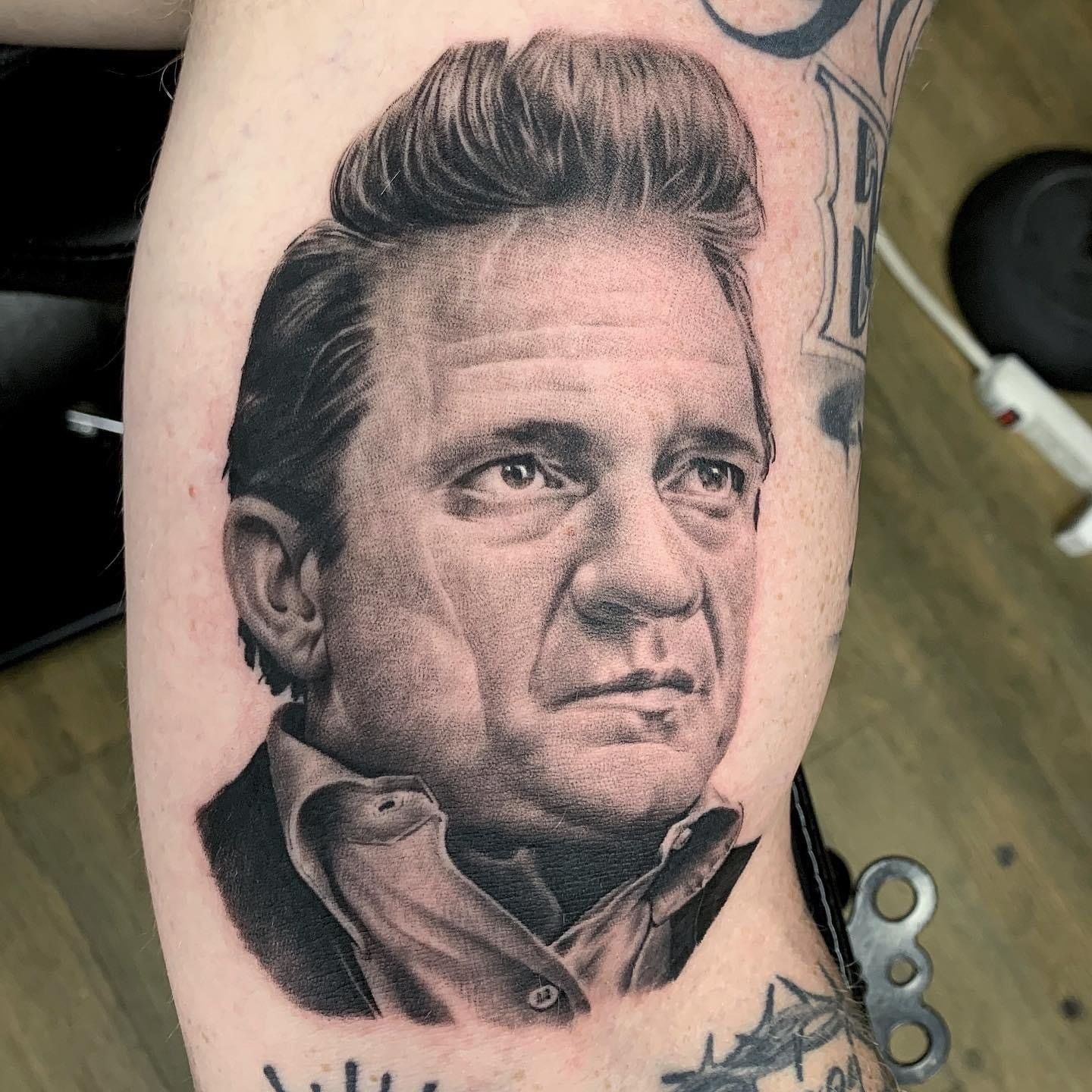 A man has a tattoo of johnny cash on his arm