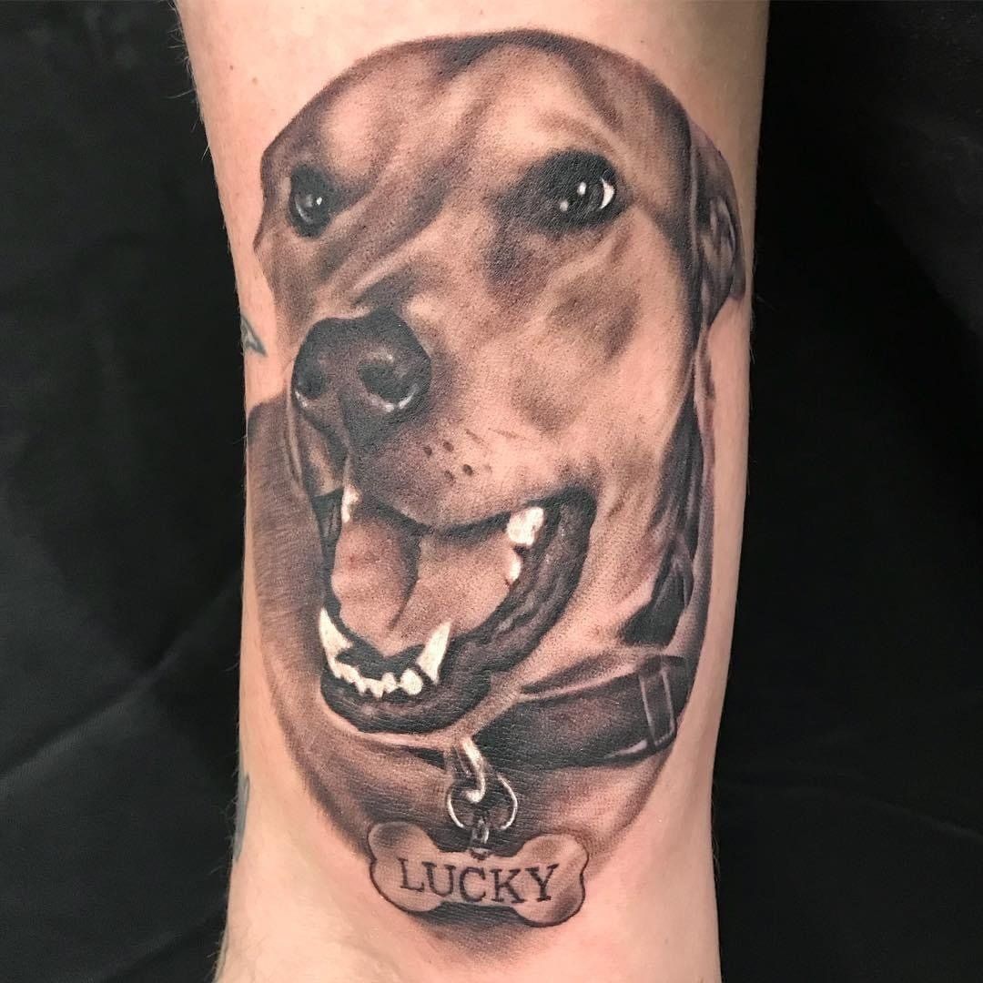 A black and white tattoo of a dog on a person 's leg.