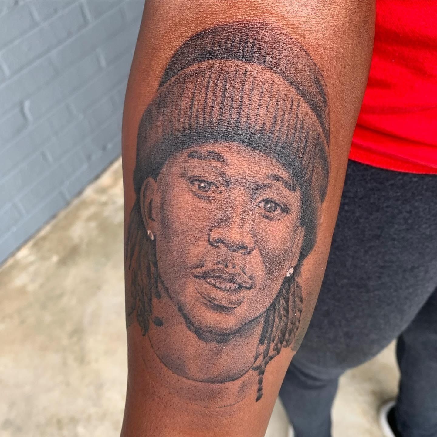 A black and white tattoo of a man wearing a beanie