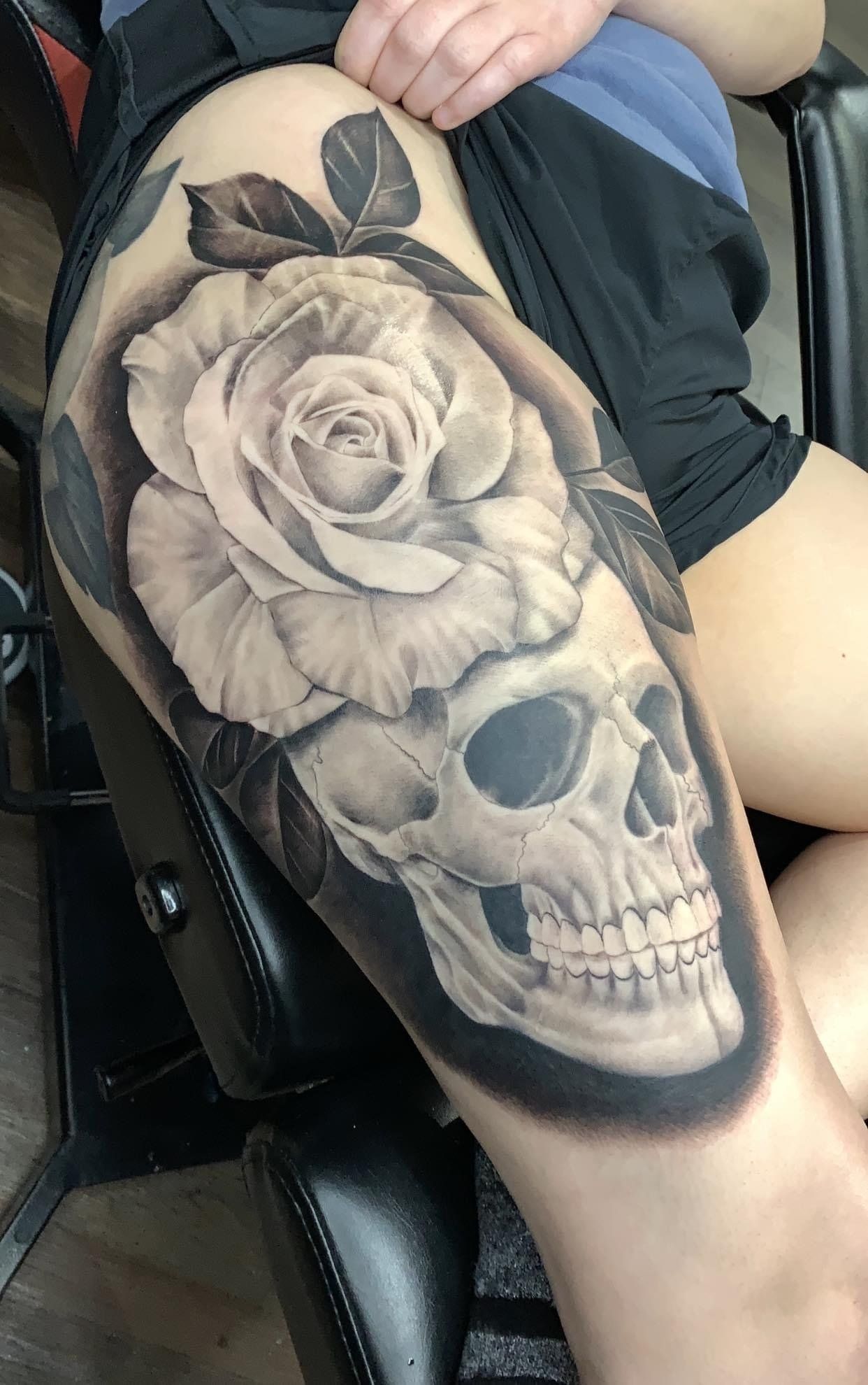 A woman has a tattoo of a skull and a rose on her leg.