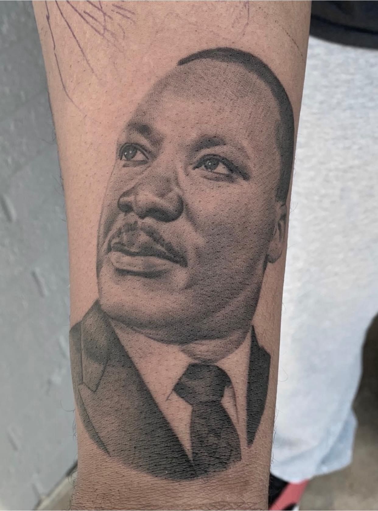 A man has a tattoo of martin luther king jr. on his arm.