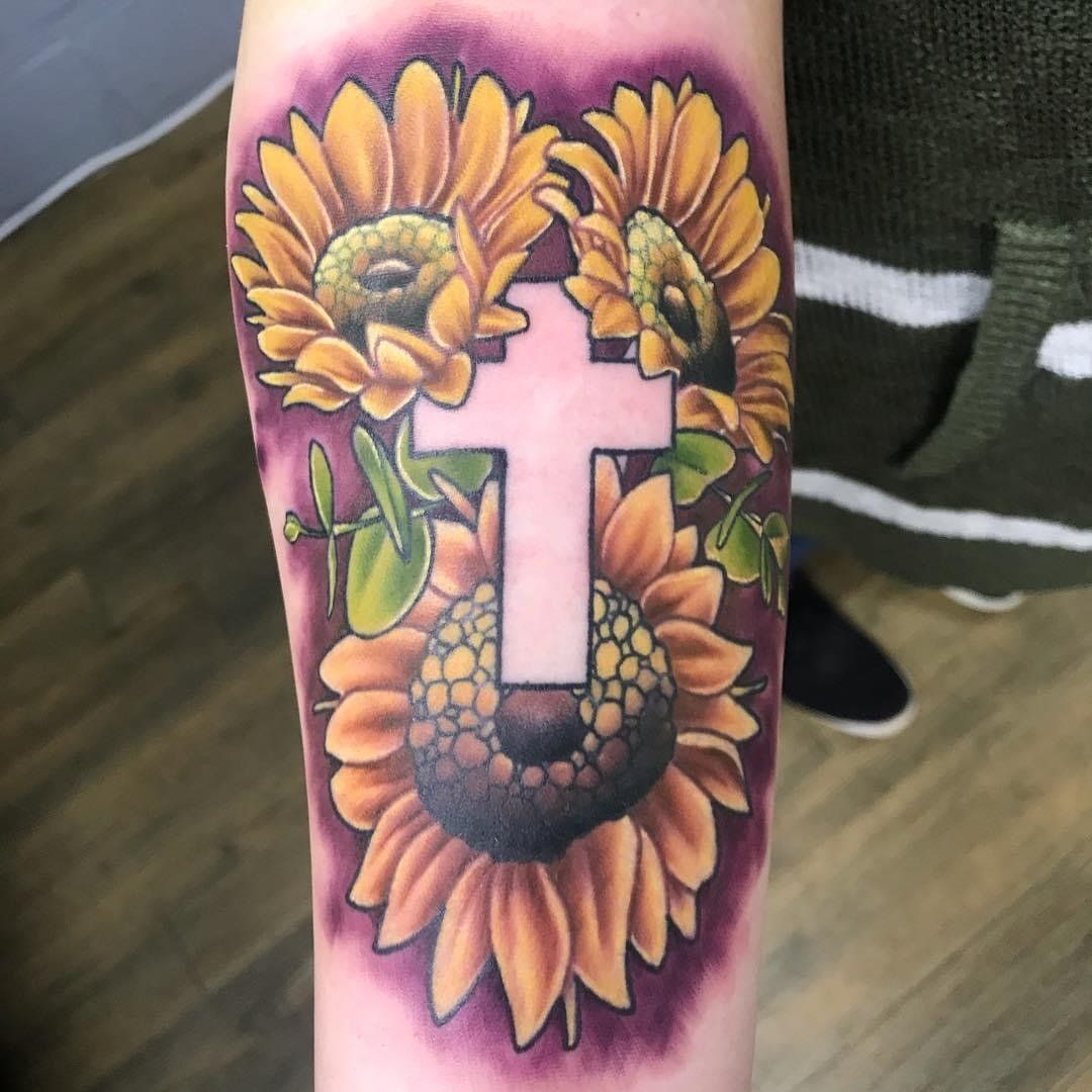 A tattoo of sunflowers and a cross on a person 's arm