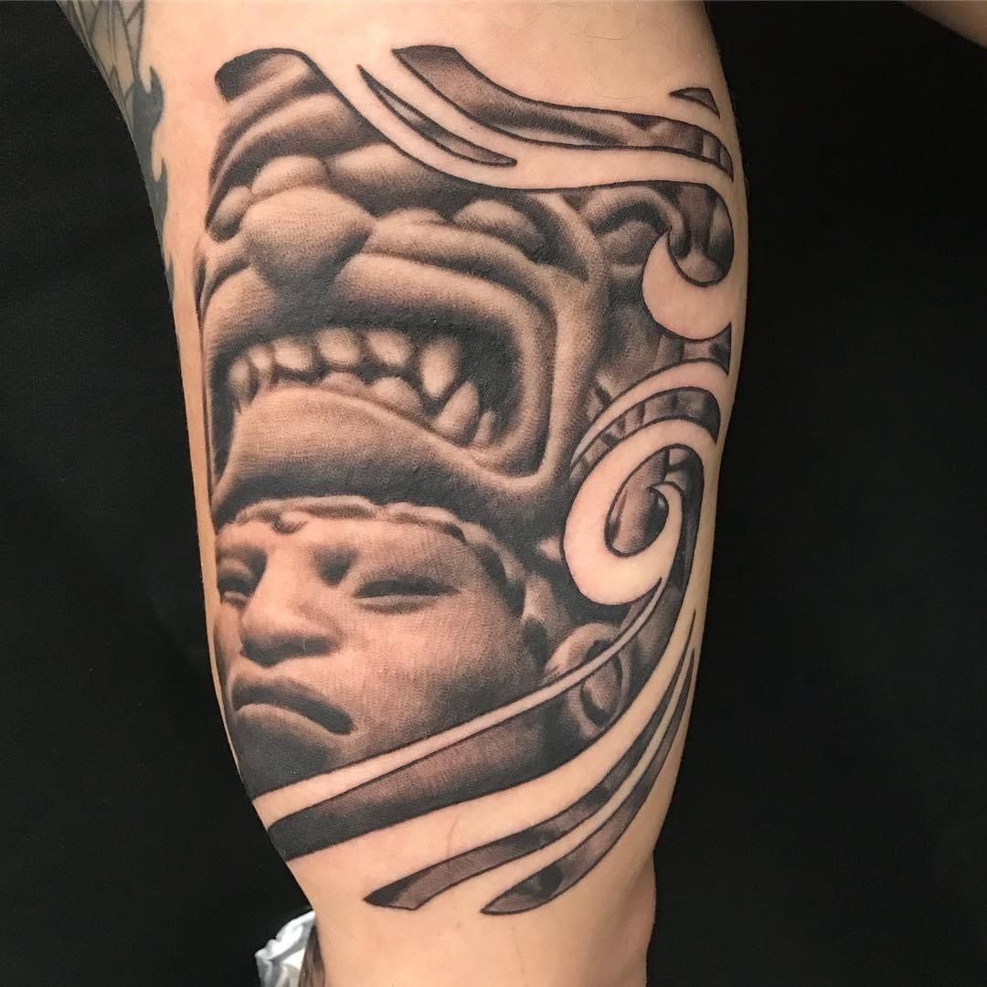 A person has a tattoo of a statue on their arm