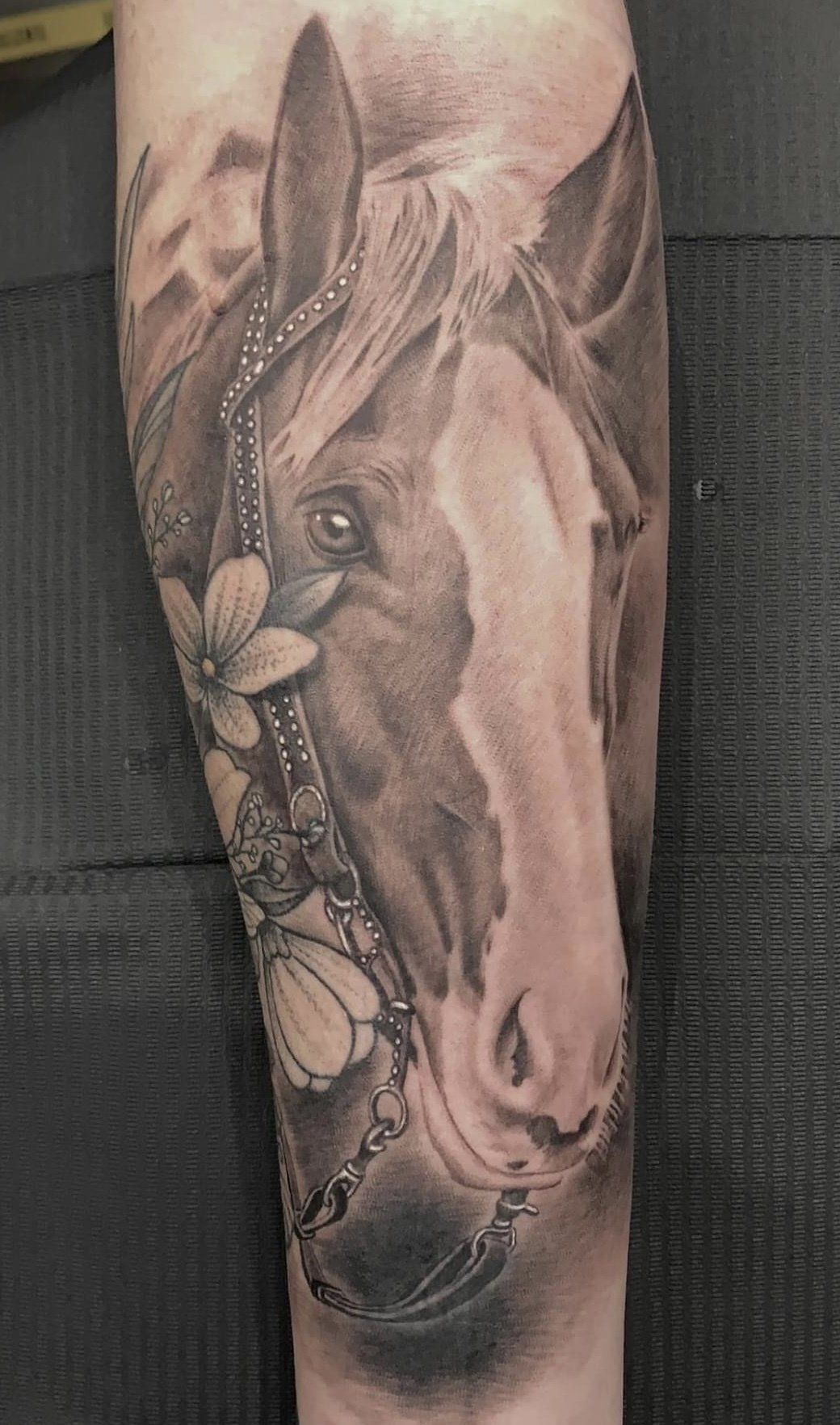 A black and white horse tattoo on a person 's arm.