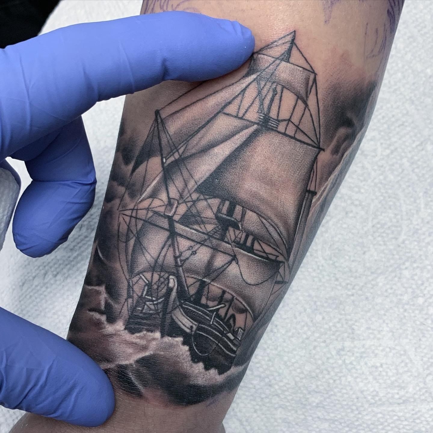 A person has a tattoo of a sailboat on their arm