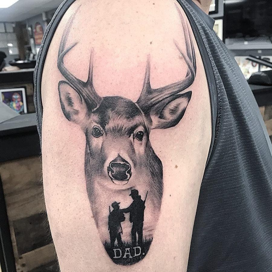 A man has a tattoo of a deer and a hunter on his arm.