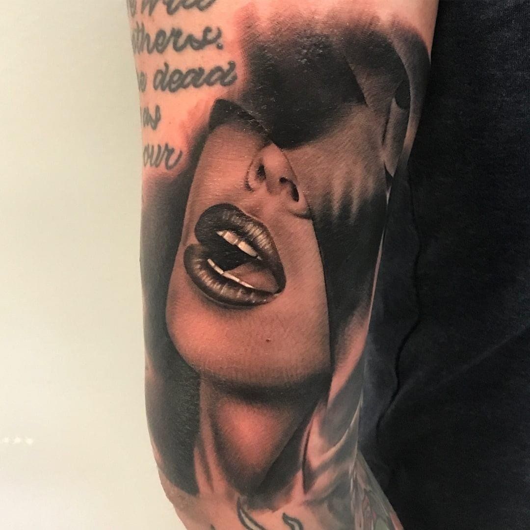 A man has a tattoo of a woman 's face on his arm.