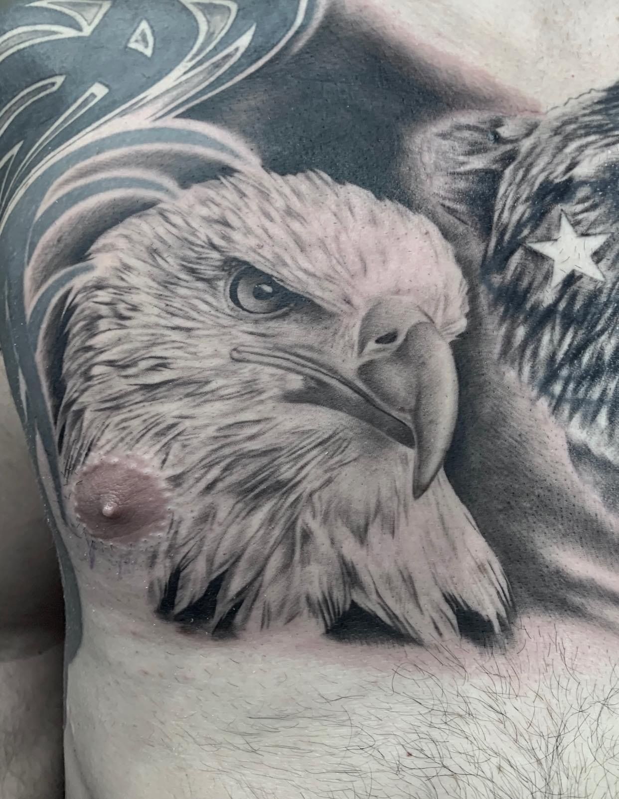 A close up of a bald eagle tattoo on a man 's chest.