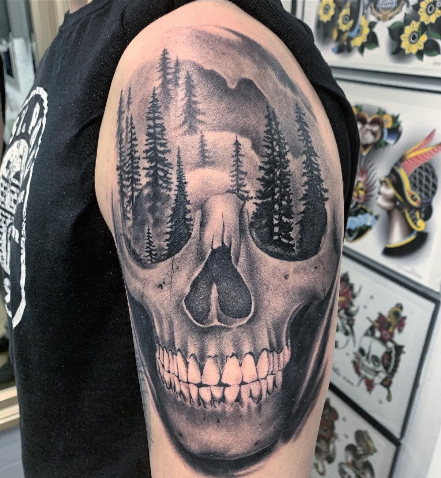 A black and white tattoo of a skull with trees in the background