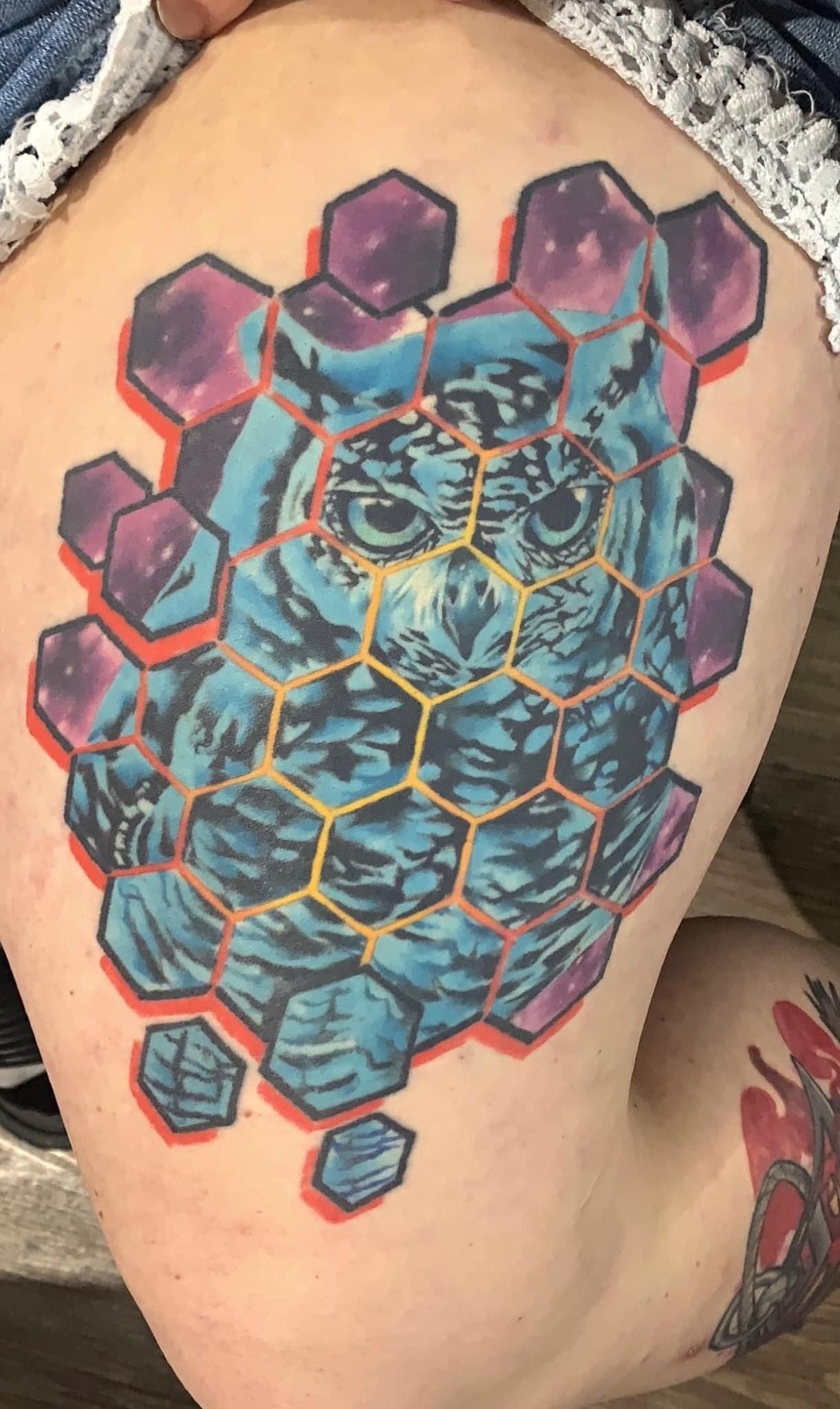 A woman has a tattoo of an owl on her thigh.