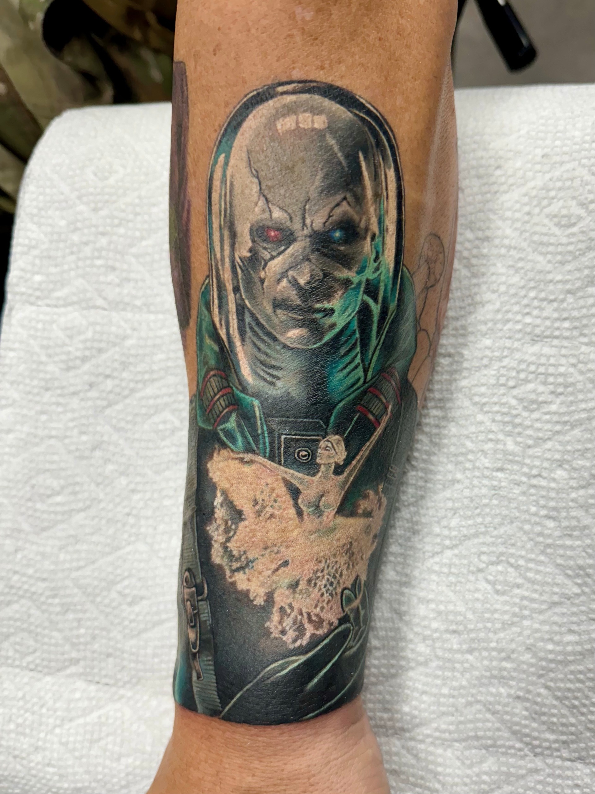 A man has a tattoo of a superhero on his forearm.