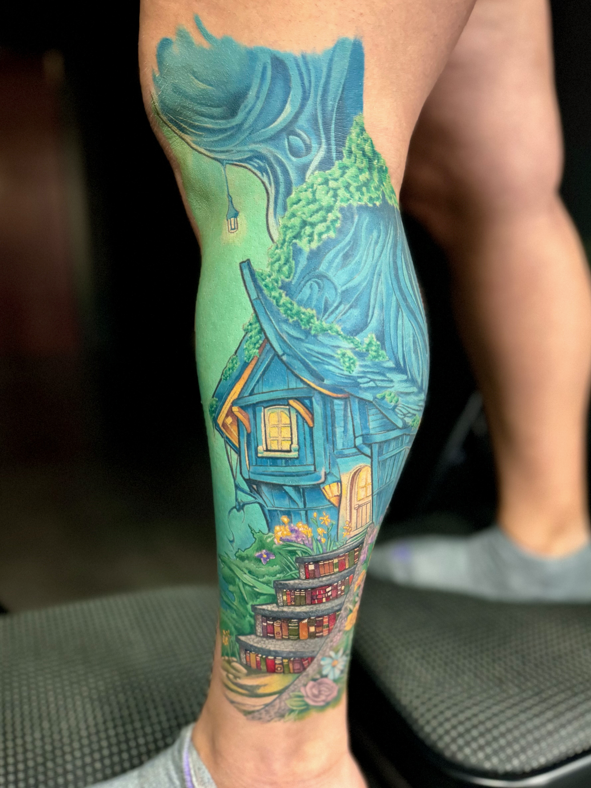 A woman has a tattoo of a house on her leg.