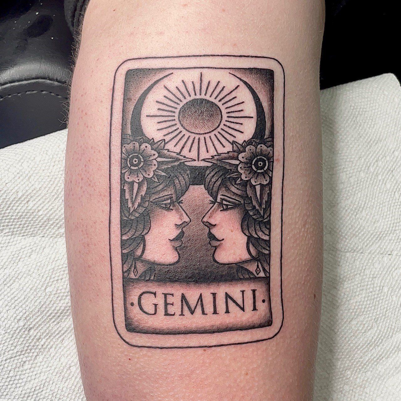 A tattoo on a person 's arm that says gemini