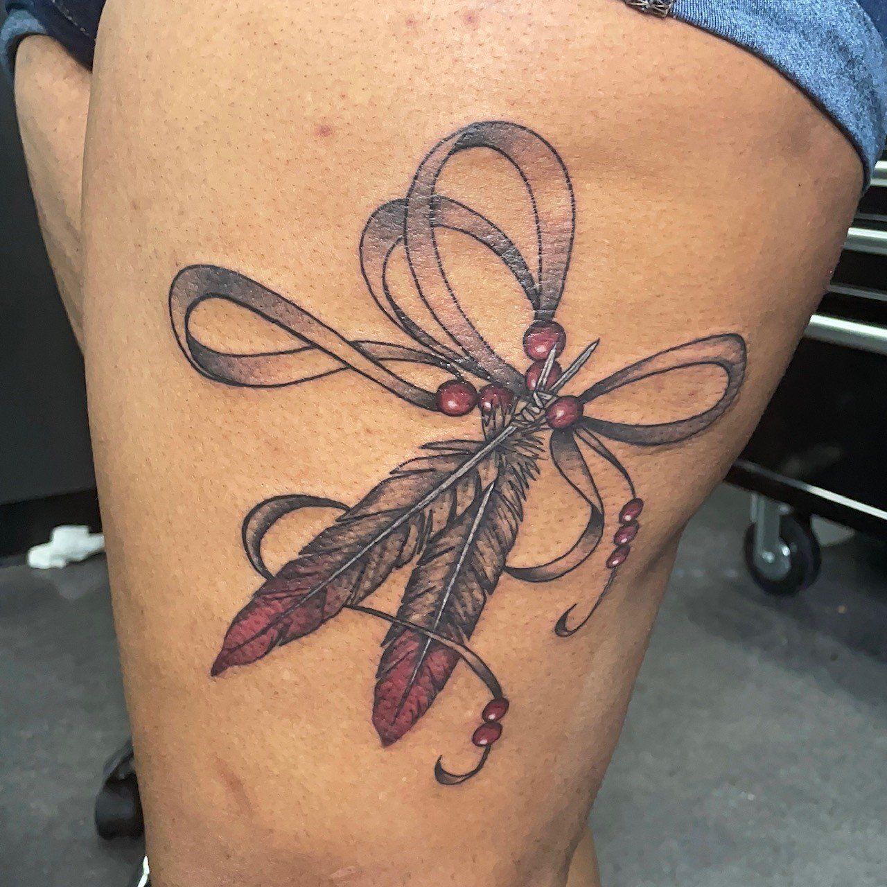 A woman has a dragonfly tattoo on her thigh