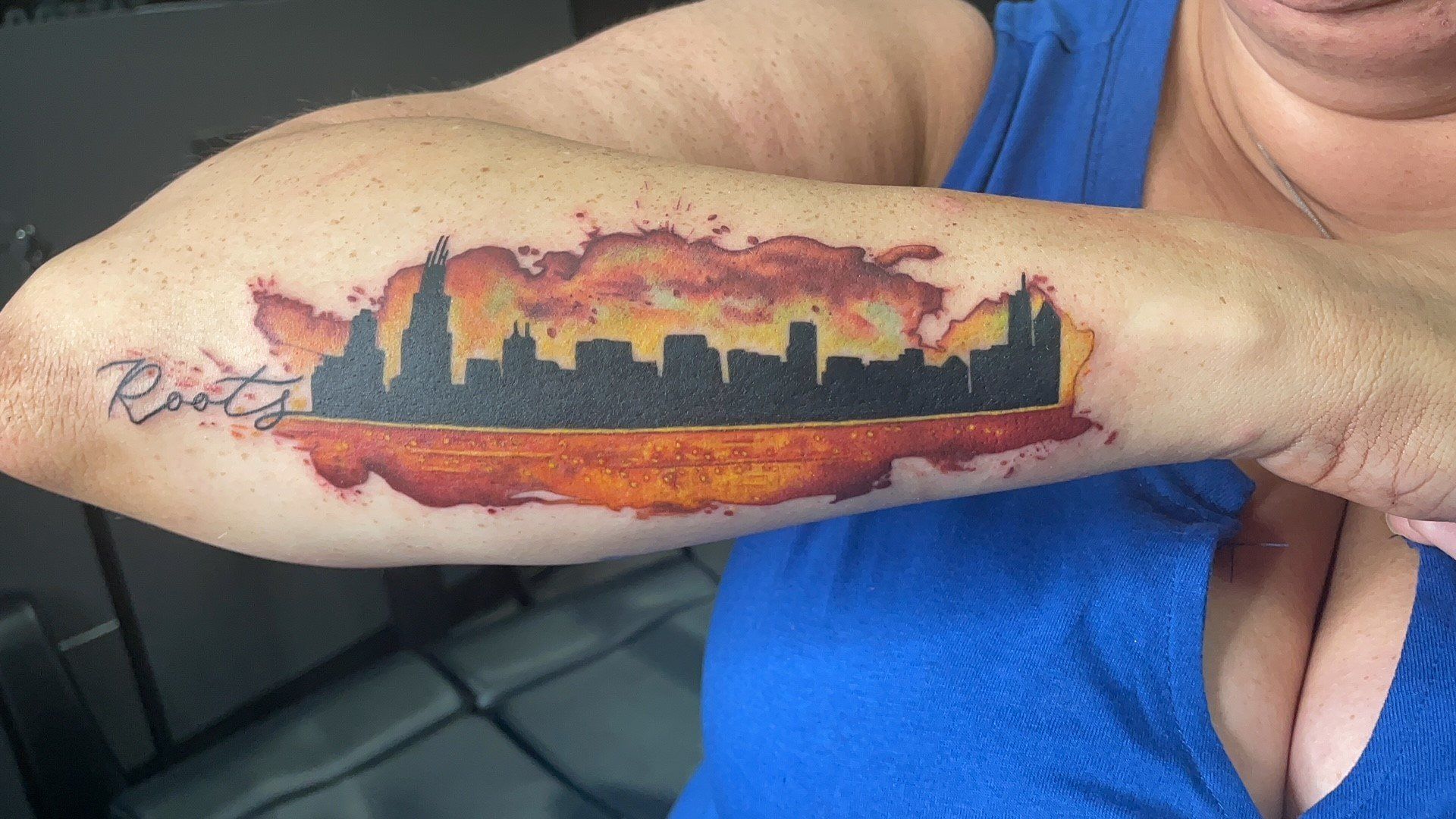 A woman has a tattoo of a city skyline on her arm.