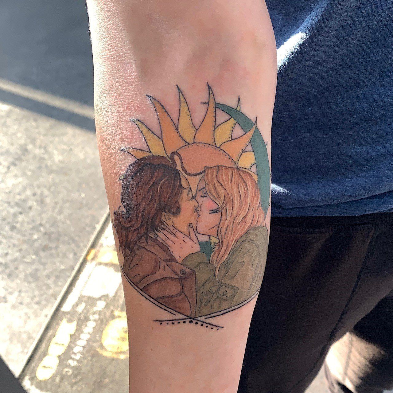 A tattoo of two women kissing with the sun in the background