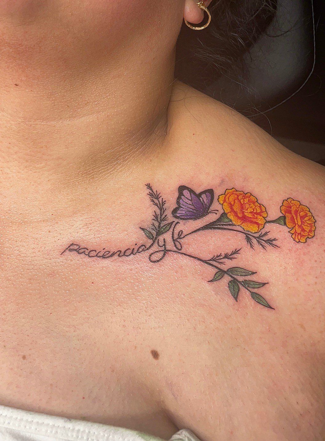 A woman has a tattoo of flowers and a butterfly on her shoulder.