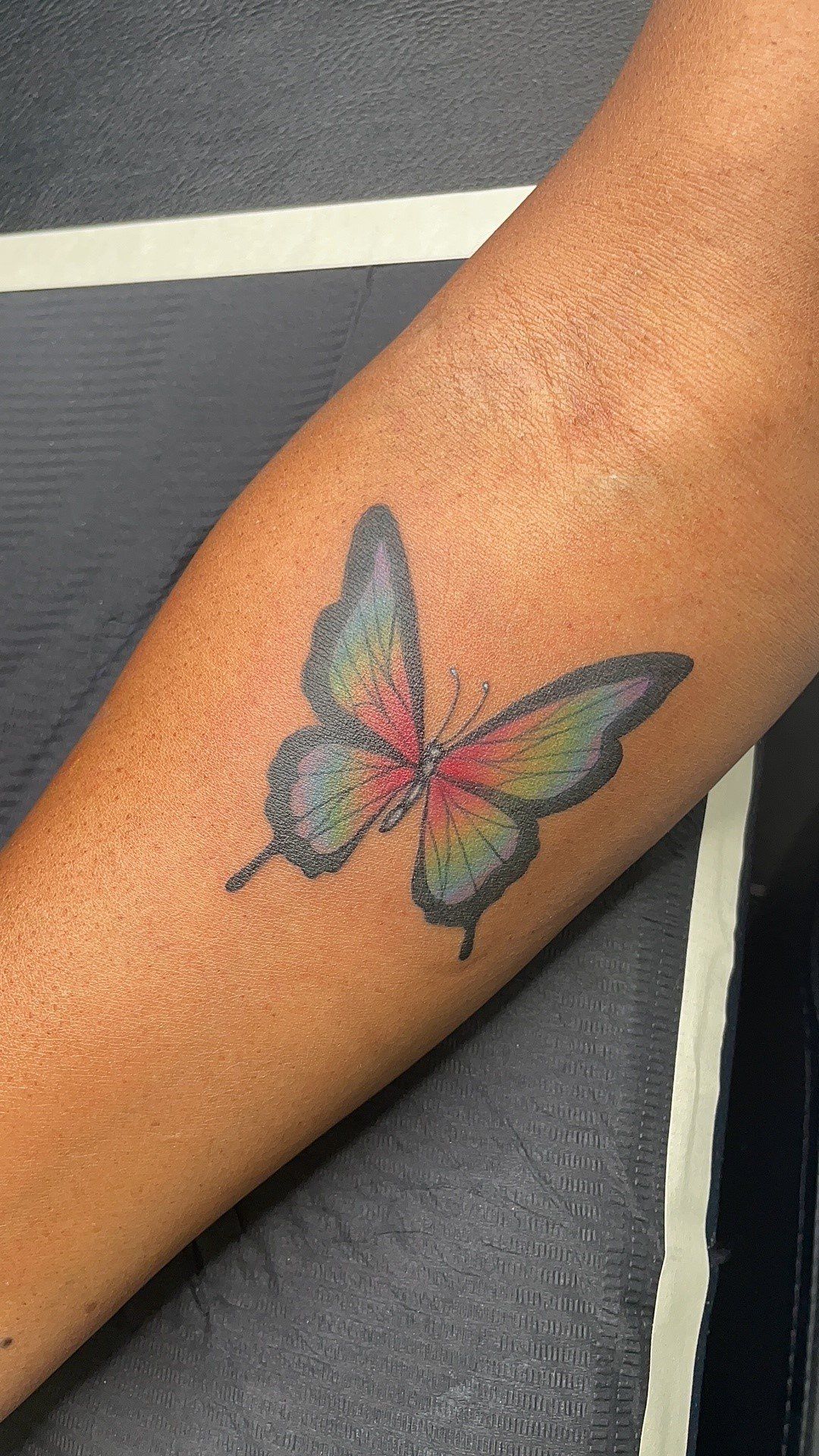 A person has a butterfly tattoo on their forearm.