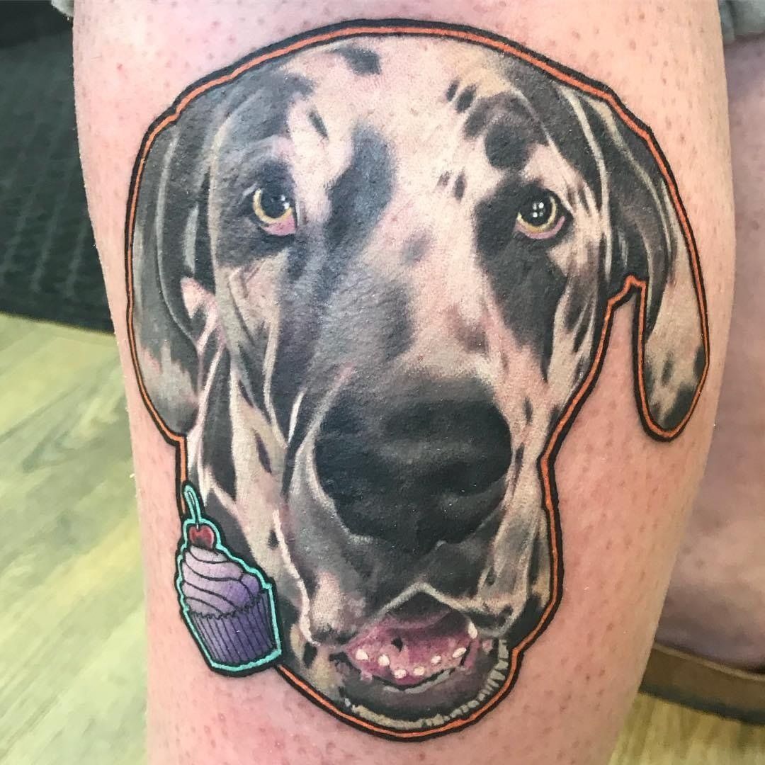 A person has a tattoo of a dog holding a cupcake on their leg.