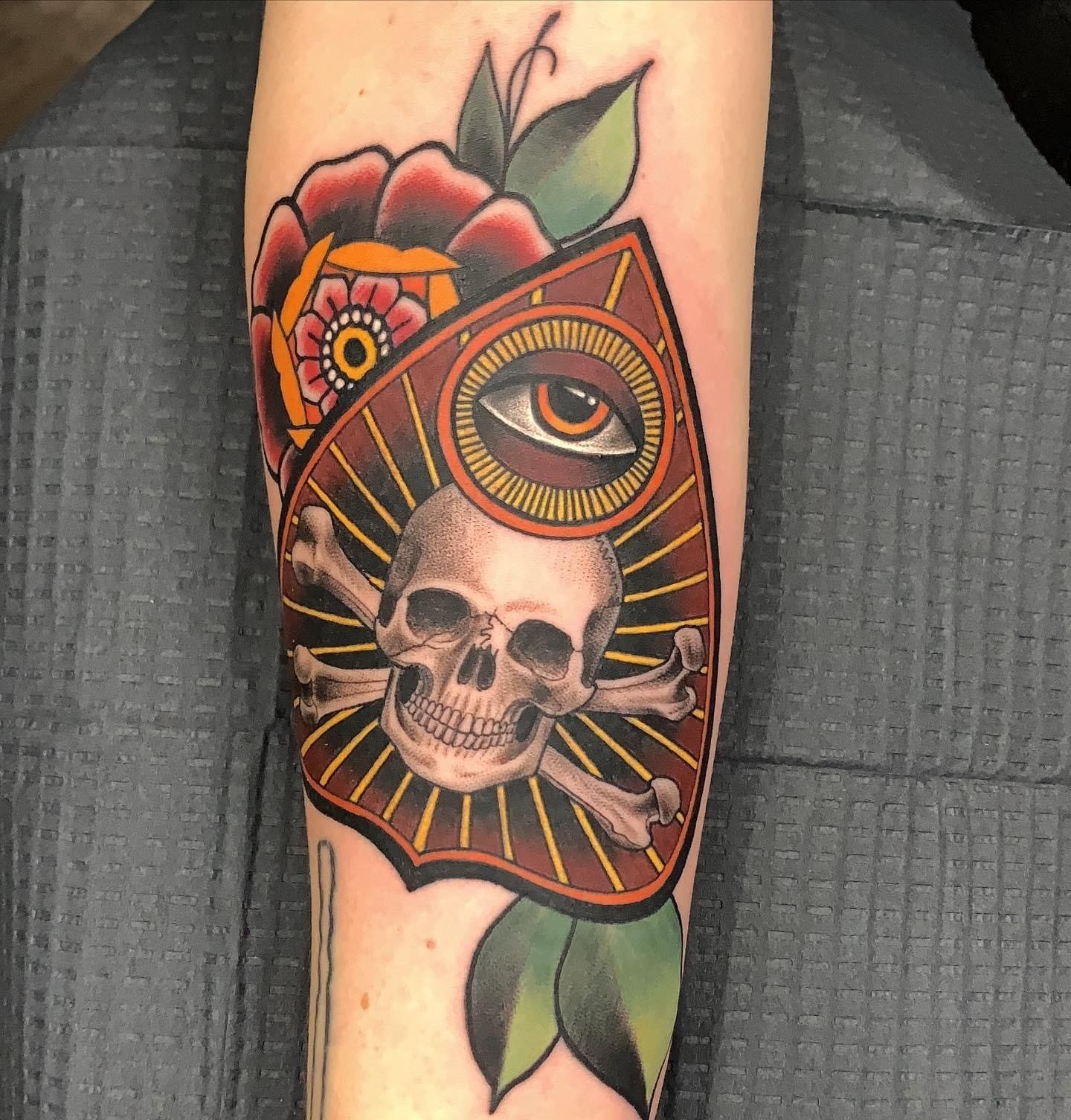 A person has a tattoo of a skull and crossbones on their forearm.