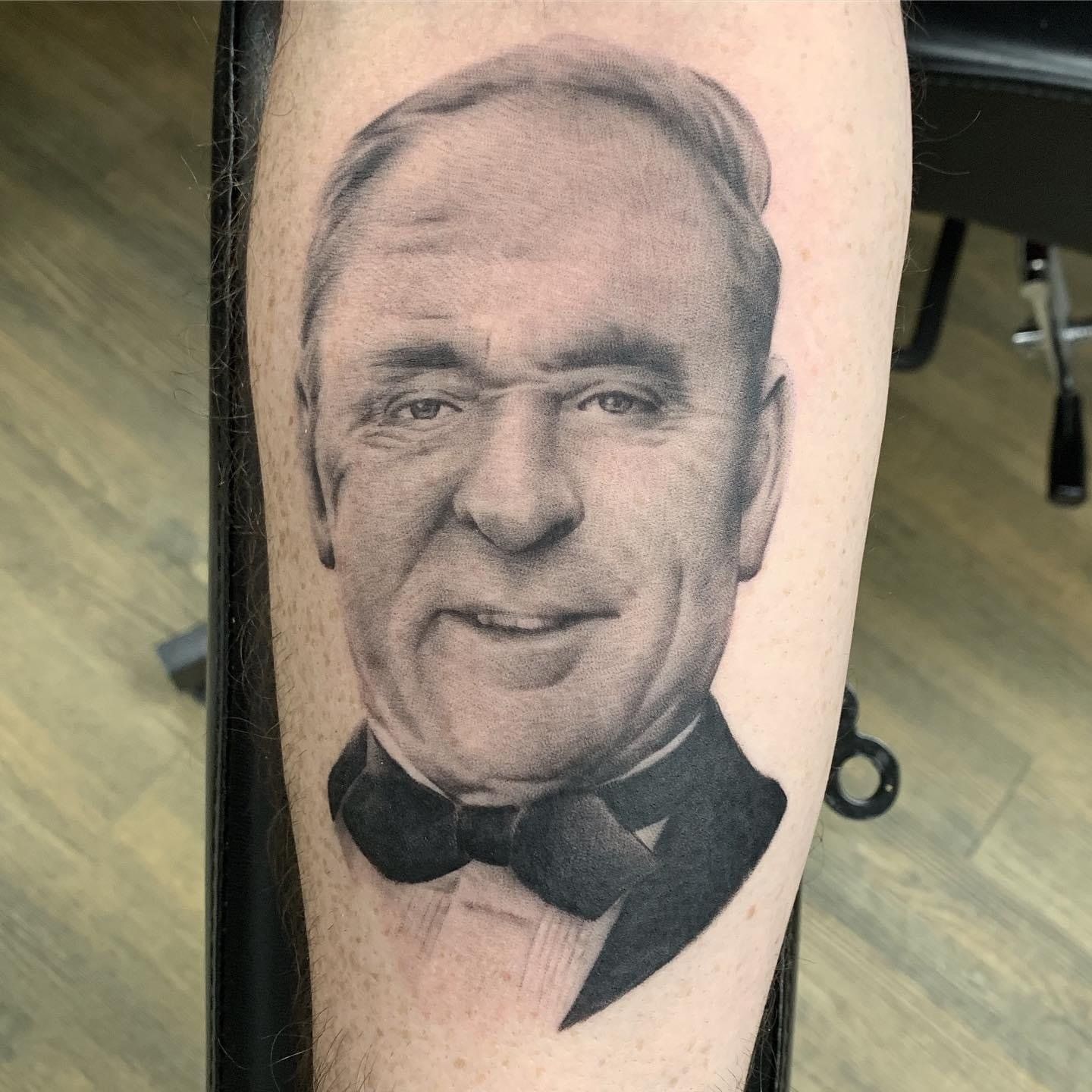 A black and white tattoo of a man in a tuxedo and bow tie