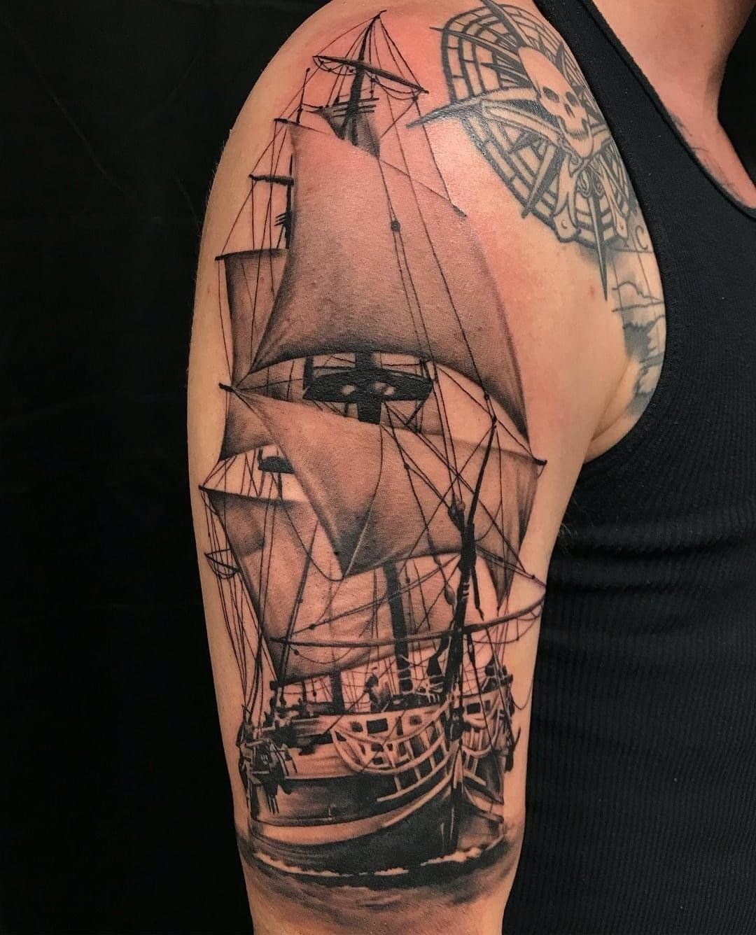 A man has a tattoo of a sailboat on his arm