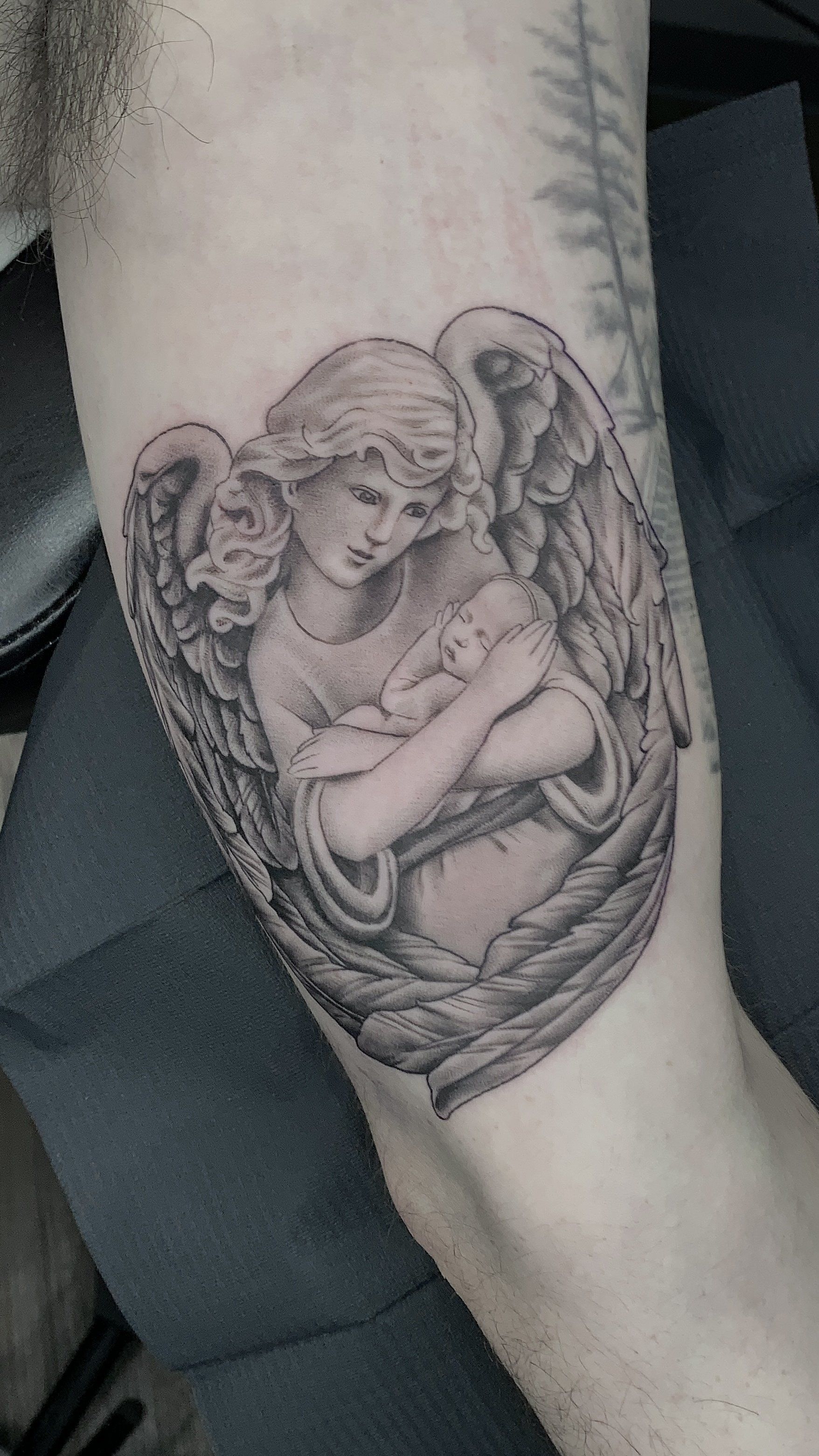 A person has a tattoo of an angel on their arm.