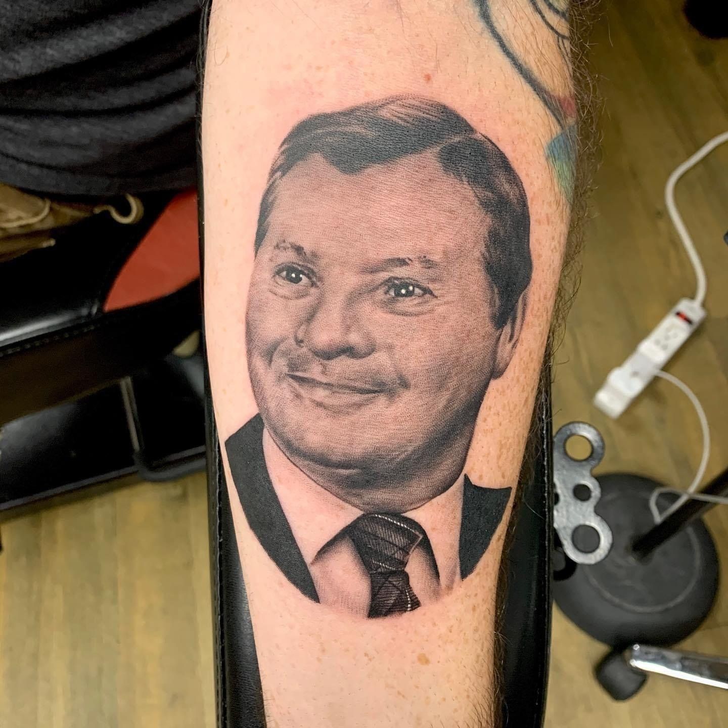 A man has a tattoo of a man in a suit and tie