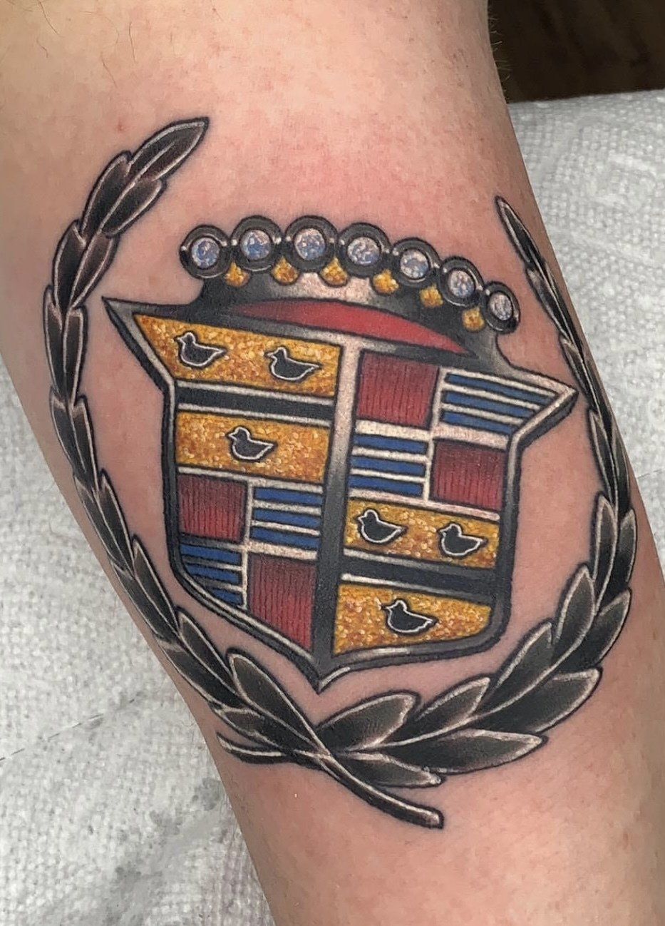 A tattoo of a cadillac logo on a person 's arm